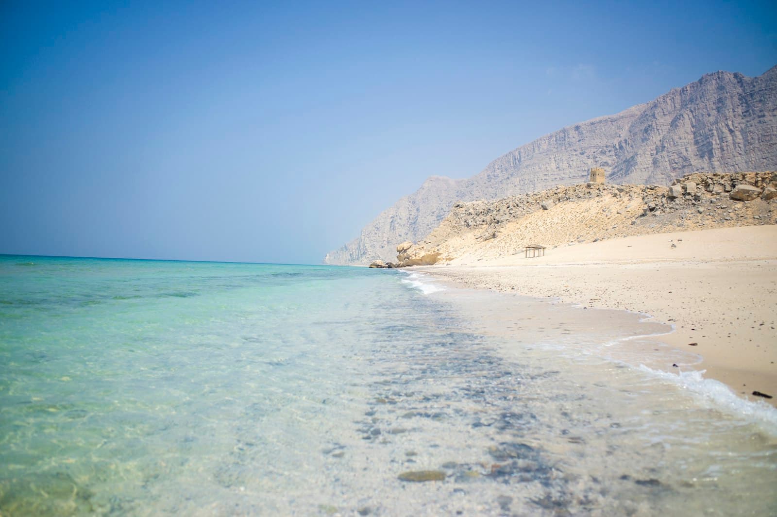 Clear turquoise water on a quiet Omani beach below the mountains