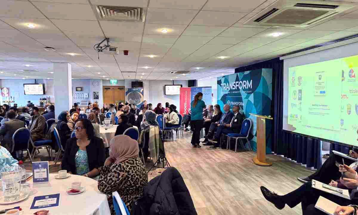 Teachers seated at round tables listening to a school presentation at a Transform recruitment fair