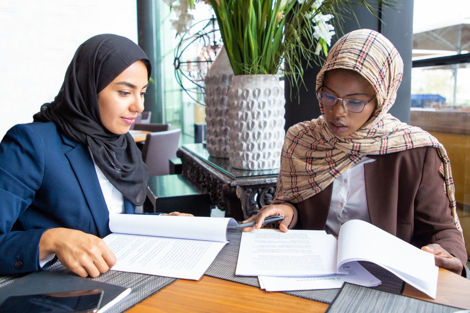 Two teachers in headscarves planning lessons together at a table