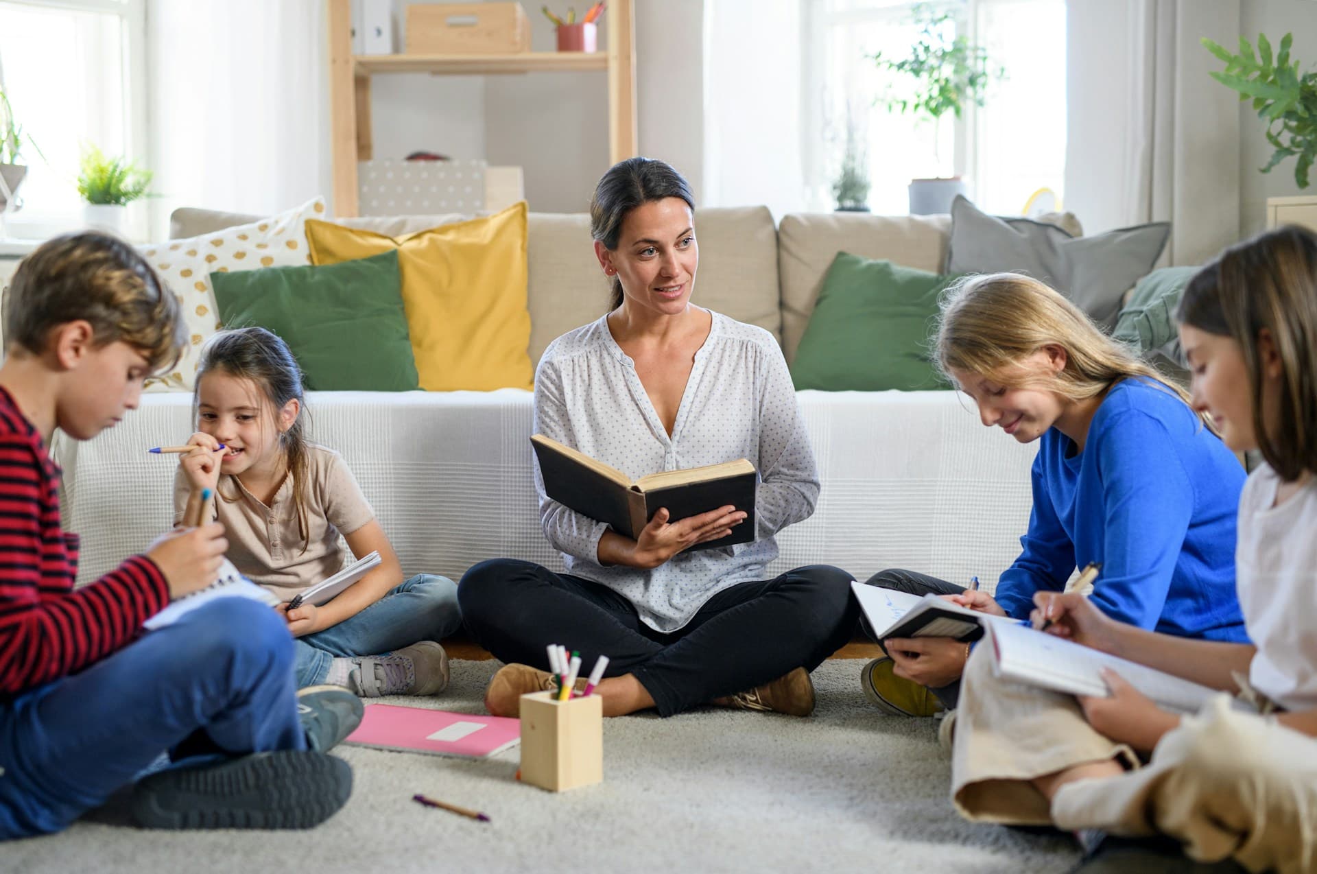 A teacher reading with a small group of children sitting on the floor